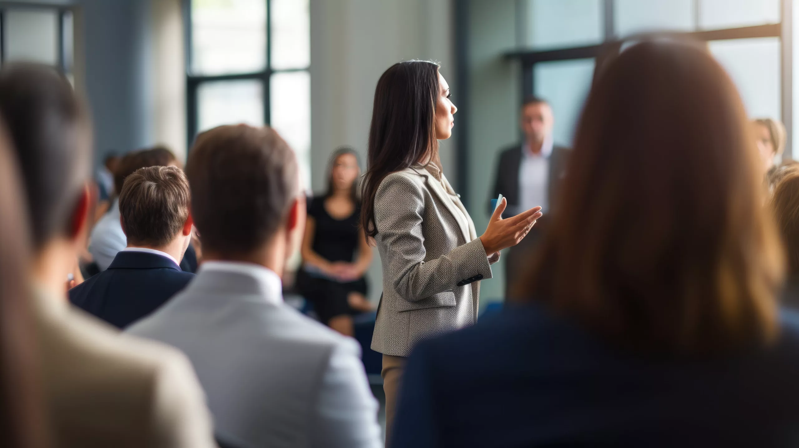 Femme en veston prenant la parole devant un groupe de collègues dans un cadre professionnel, illustrant un acte de courage en milieu de travail.