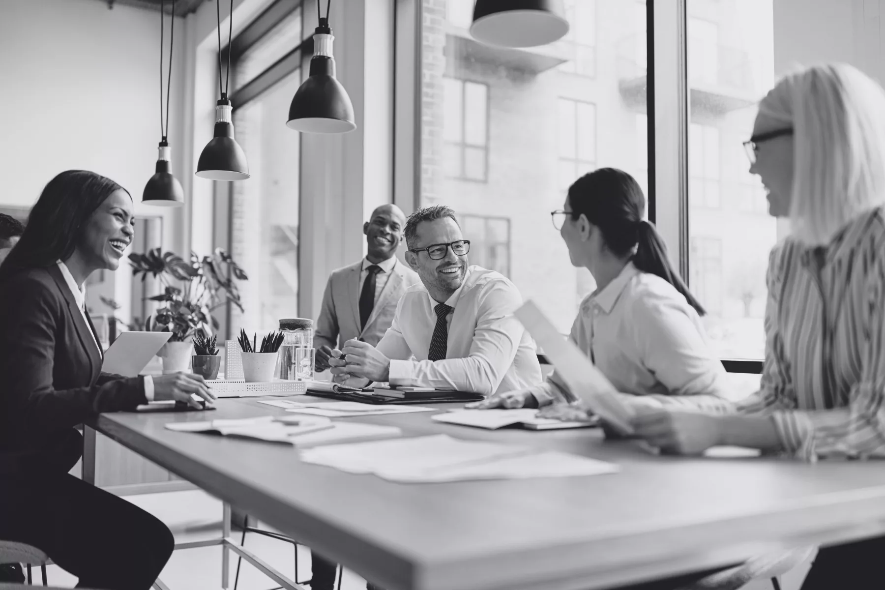 Groupe de professionnel·le·s en réunion, souriant·e·s et engagé·e·s dans une discussion collaborative autour d’une table de travail.